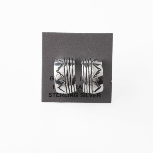 Pair of silver earrings with stamped design on a gray card with 'Sterling Silver' text.