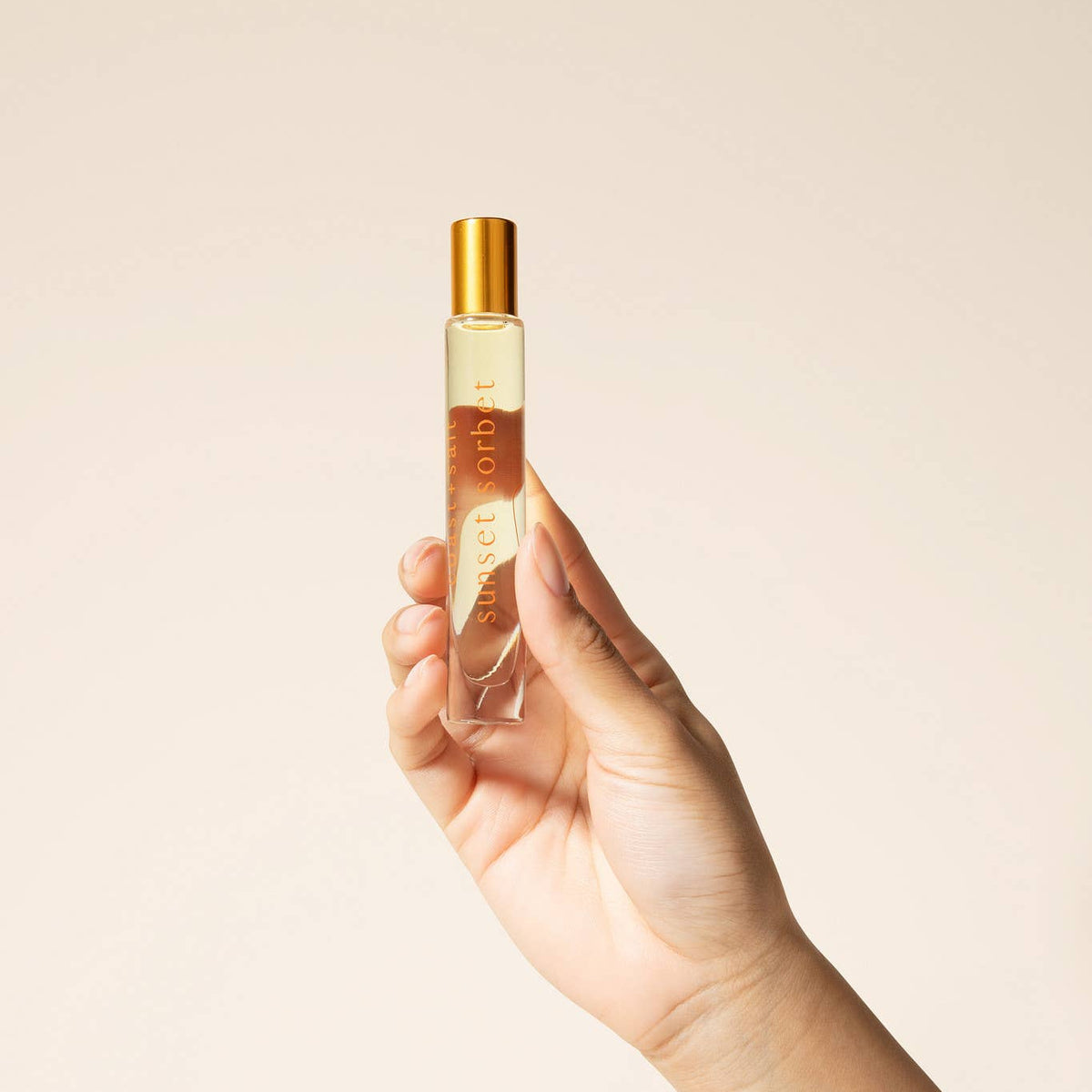 Hand holding a perfume bottle against a plain background