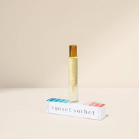 Roll-on bottle of 'Sunset Sorbet' with its packaging on a beige background