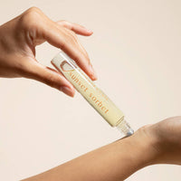 Hand applying a cosmetic product labeled 'Sunset Sorbet' to a wrist against a beige background