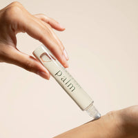 Hand applying a skincare product labeled 'Palm' to a wrist against a beige background