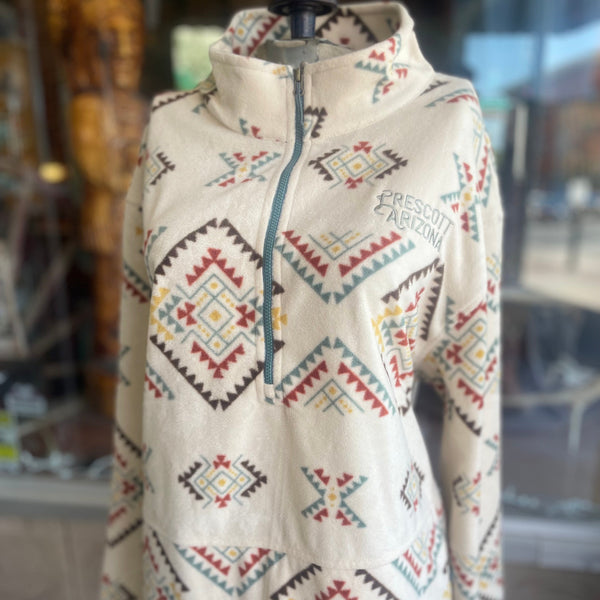 Beige fleece jacket with colorful geometric patterns on a mannequin against a blurred indoor background.