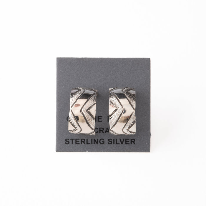 Pair of silver earrings with stamped design on a gray card with 'Sterling Silver' text.