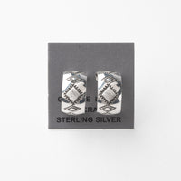 Pair of silver earrings with stamped design on a gray card with 'Sterling Silver' text.