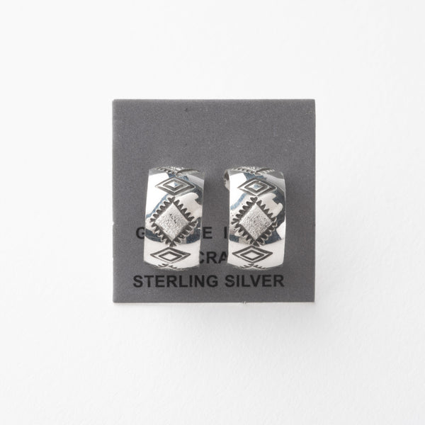 Pair of silver earrings with stamped design on a gray card with 'Sterling Silver' text.