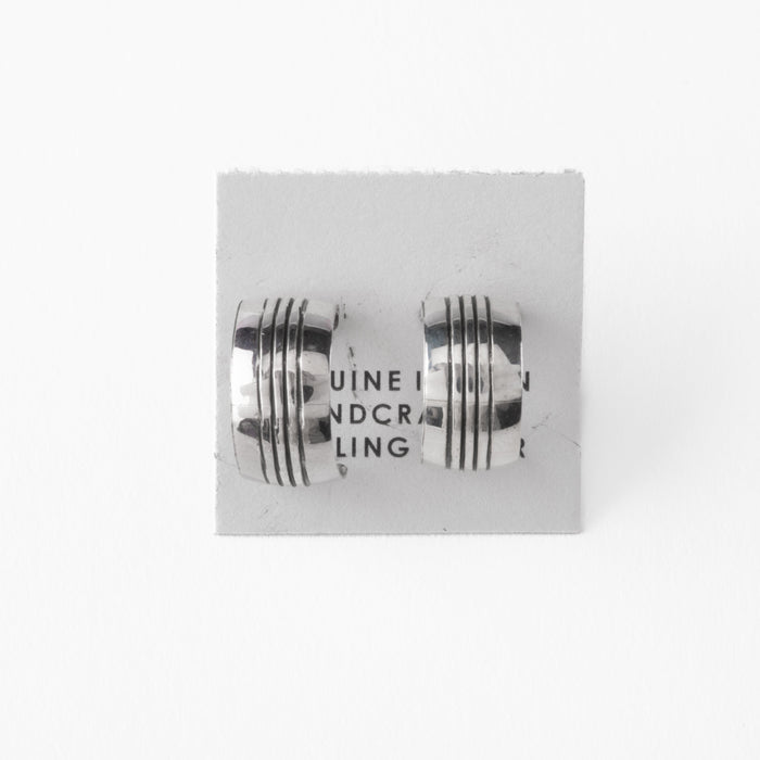 Pair of silver earrings with stamped design on a gray card with 'Sterling Silver' text.