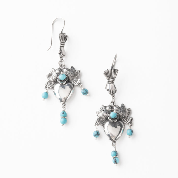 Pair of silver earrings with turquoise stone, and a heart surrounded by birds on a white background