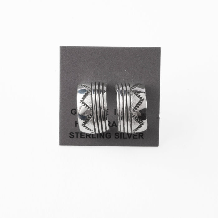 Pair of silver earrings with stamped design on a gray card with 'Sterling Silver' text.