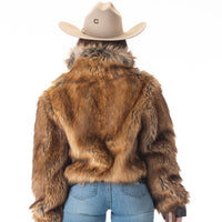 Person wearing a fur jacket, cowboy hat, and holding a gun on a white background