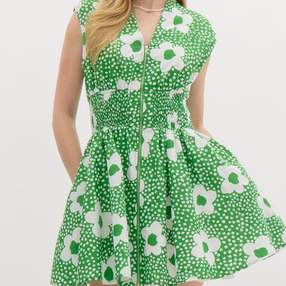 Green Floral print v-neck sleeveless mini dress featuring zipper closure at front. Smocking at waist. Pocket at sides. Lined. Woven. Non-sheer. Lightweight.