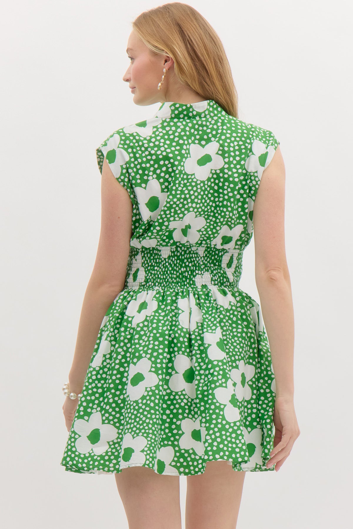 Green Floral print v-neck sleeveless mini dress featuring zipper closure at front. Smocking at waist. Pocket at sides. Lined. Woven. Non-sheer. Lightweight.