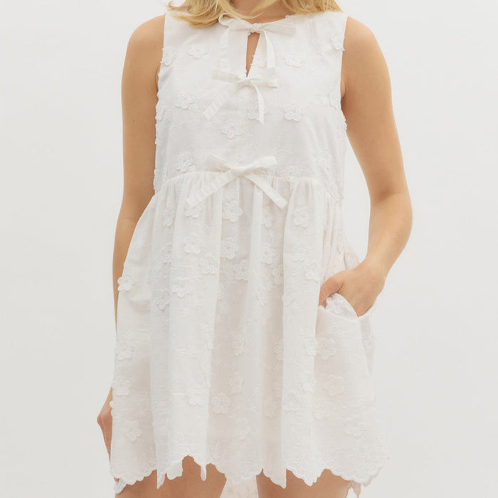 Off White: Solid sleeveless floral appliqué pullover dress featuring embroidered scallop hem. Front bow tie closure. Pockets at sides. Lined. Woven. Non-sheer. Lightweight.