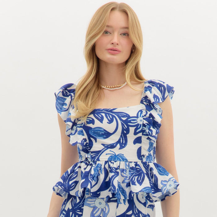 Tropical print elasticated shoulder flutter sleeve ruffle hem pullover top. Smocked closure at sides. Lined. Woven. Non-sheer. Lightweight.