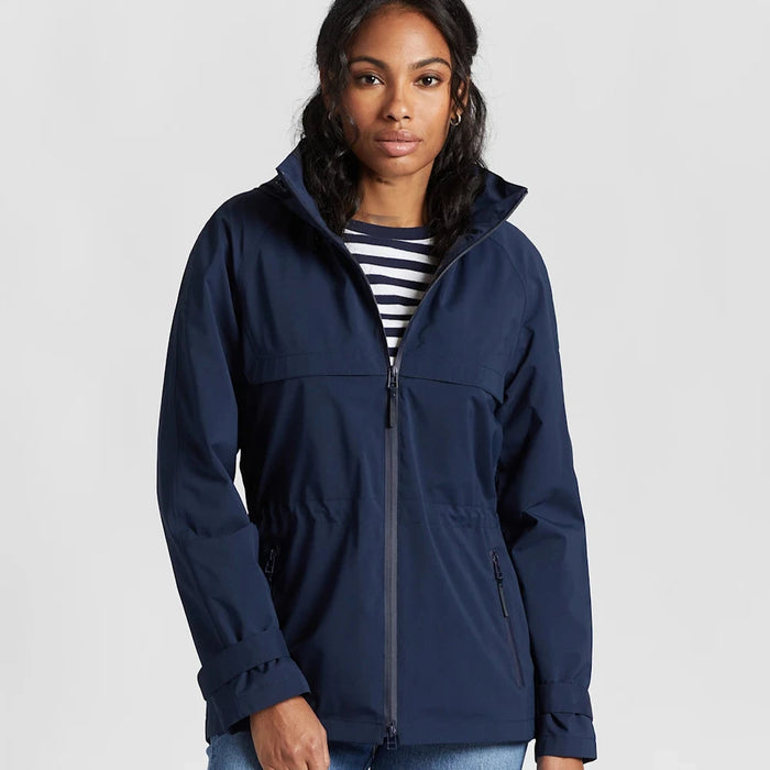 A woman wearing a navy blue zip-up jacket with a hood, over a striped top, paired with blue jeans.