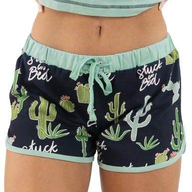 A pair of women's blueberry blue pajama shorts with an all over cactus design and the phrase 'Stuck in Bed' printed on the waistband.