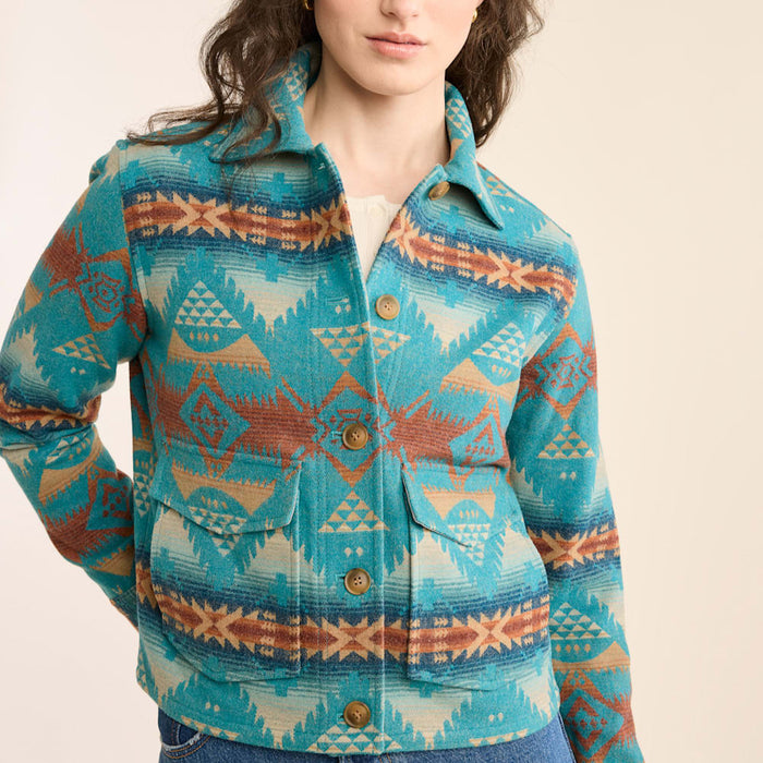 A woman wearing a multicolored wool jacket with a geometric pattern, featuring a button front and two front patch pockets.