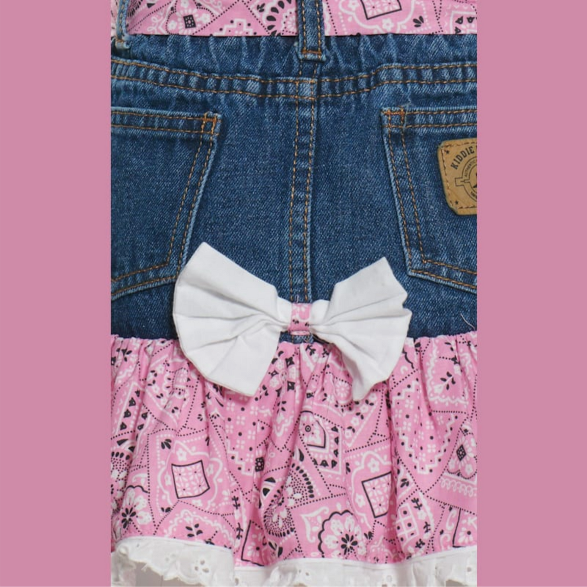 Close-up of denim and pink patterned fabric with a white bow on a pink background