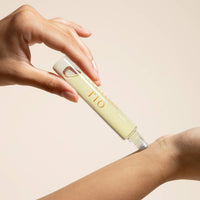 Hand holding a skincare product labeled 'RIO' on a beige background